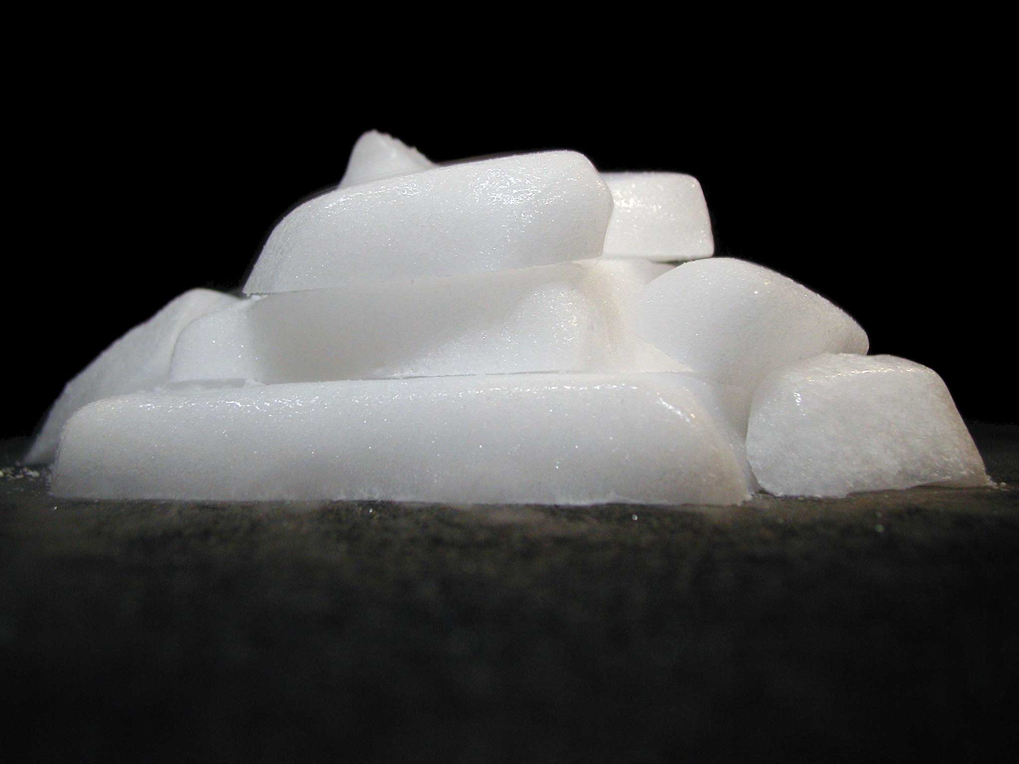 Chunks of dry ice sitting on a black surface with visible condensation