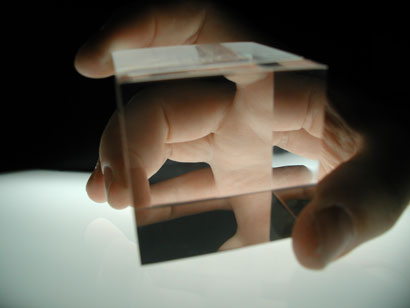 Hand holding a transparent cube, lit from below