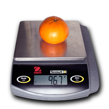 Tangerine on an electronic balance reading 96.7 grams